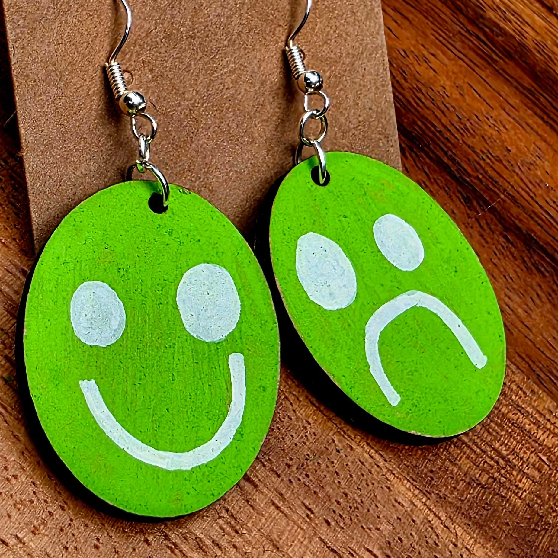 Green smiley face and sad face earrings on a brown card with 'Shellyville.com' text.
